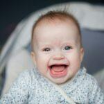 Portrait of adorable smiling baby infant showing first teeth.