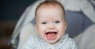 Portrait of adorable smiling baby infant showing first teeth.