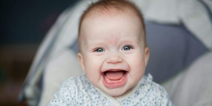 Portrait of adorable smiling baby infant showing first teeth.